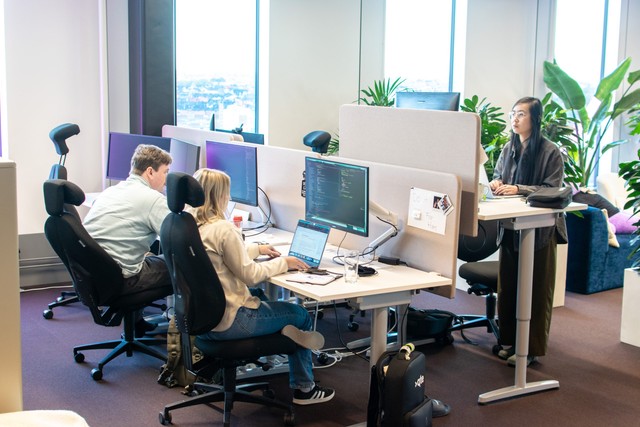 Tre kollegor sitter på kontoret och jobbar framför sina datorskärmar.